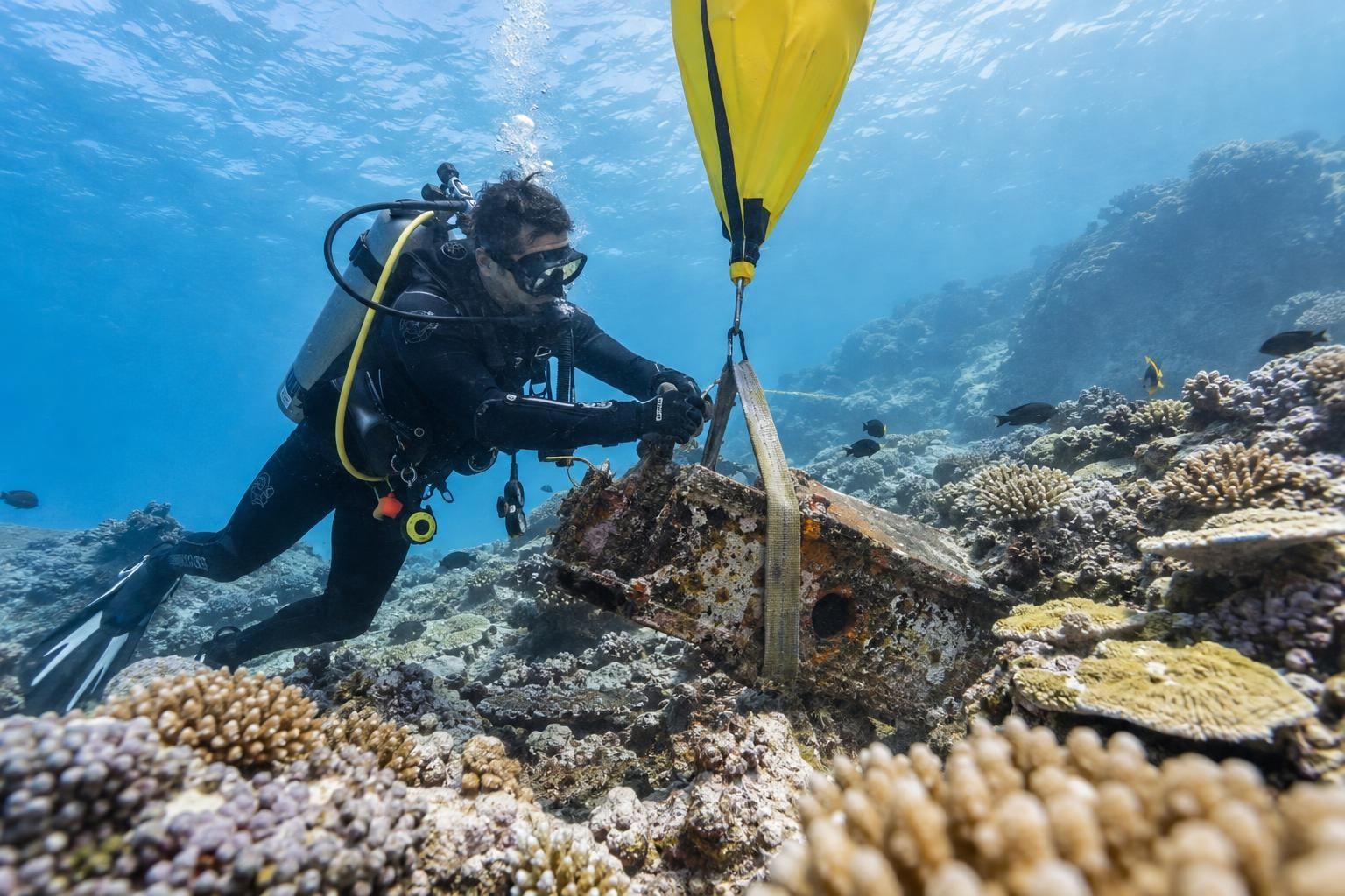Un plongeur retire un déchet métallique immergé près d’un récif corallien à La Réunion